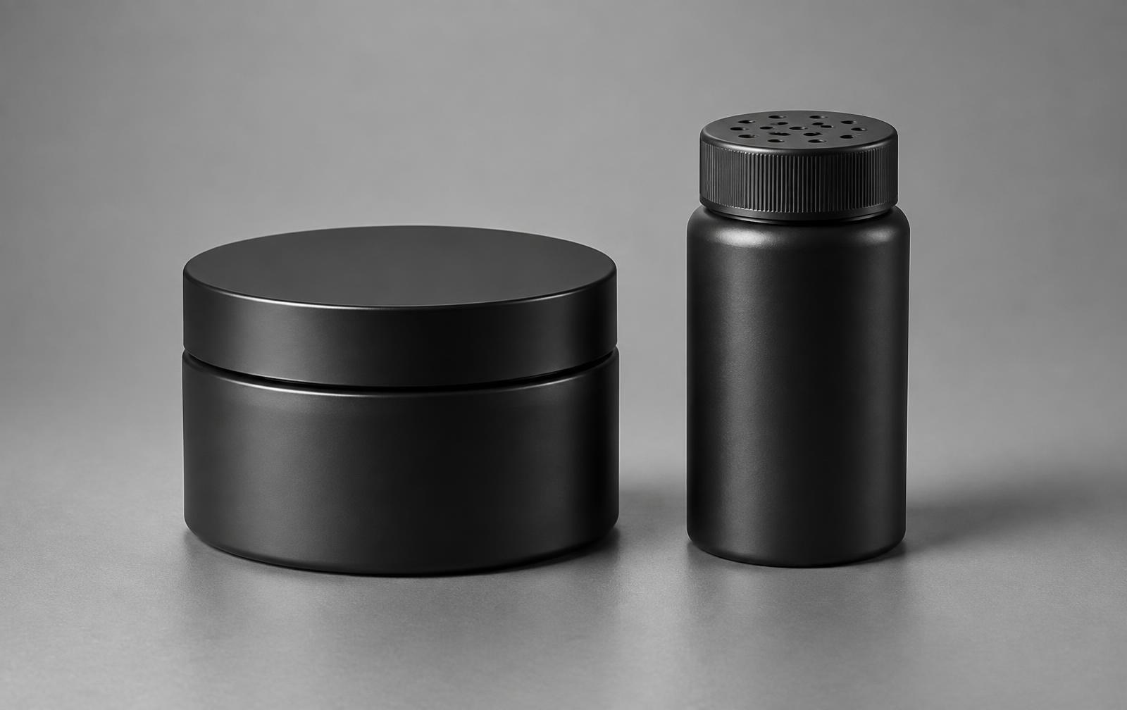 A matte black styling clay jar beside a matte black texture powder shaker on a titanium silver background.